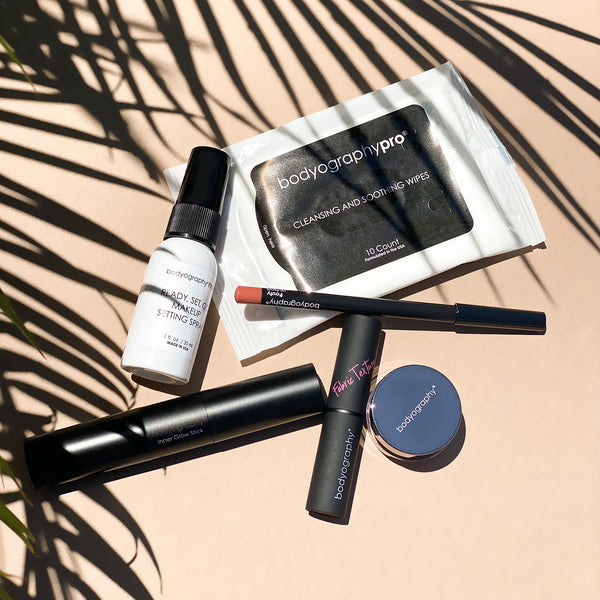 Bodyography Beauty Editor Go-To Collection: From top to bottom - Palm leaves, Mini Ready Set Go Makeup Setting Spray, 10 count Cleansing and Soothing Wipes, Lip Pencil in Pouty, Inner Glow Stick, Fabric Texture Lipstick in Chiffon, Glitter Pigment in Celestial